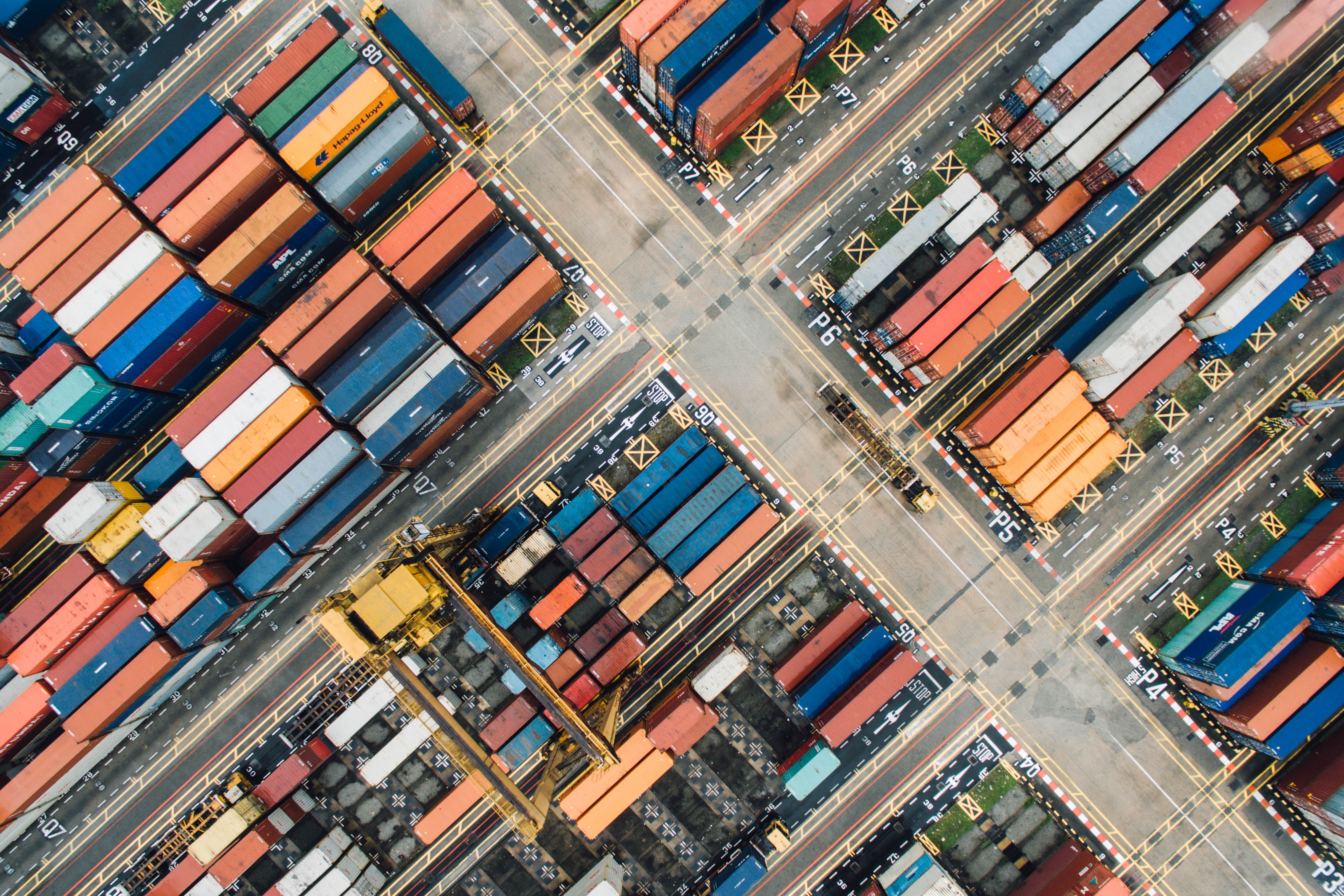 A shipping yard from above,
with rows of colorful stacked shipping containers
