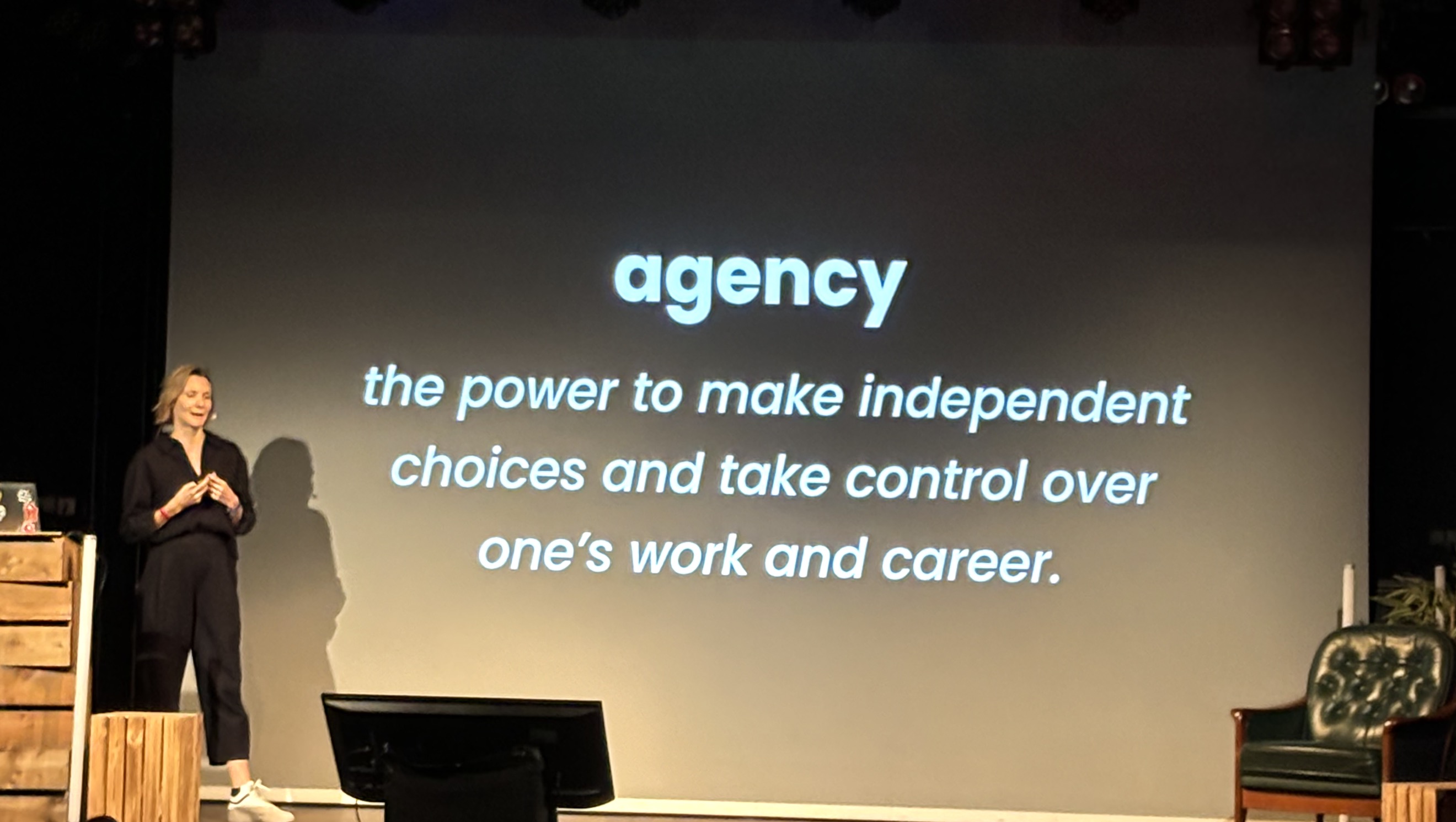 Christine in front of a slide that defines the word agency, the power to make independent choices and take control over ones work and career.
